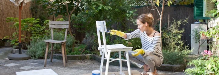 Person streicht Stuhl im Garten