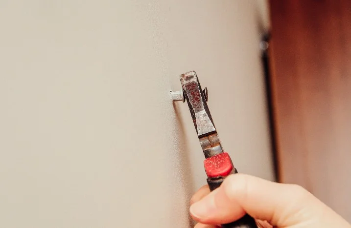 Hand befestigt Dübel mit Zange an Wand