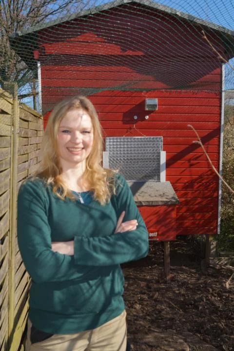 Person vor einem roten Hühnerstall