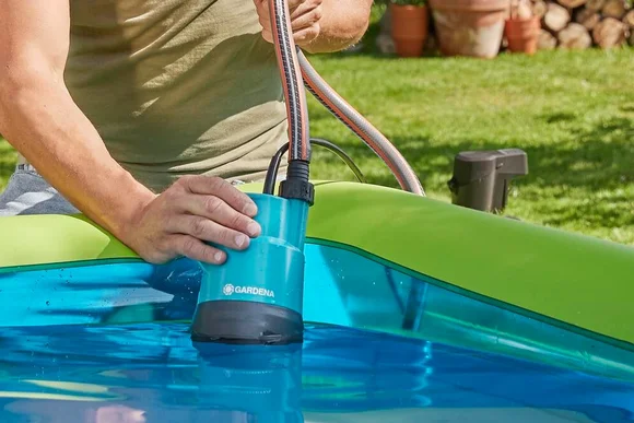 Person benutzt Pumpe um Pool zu leeren