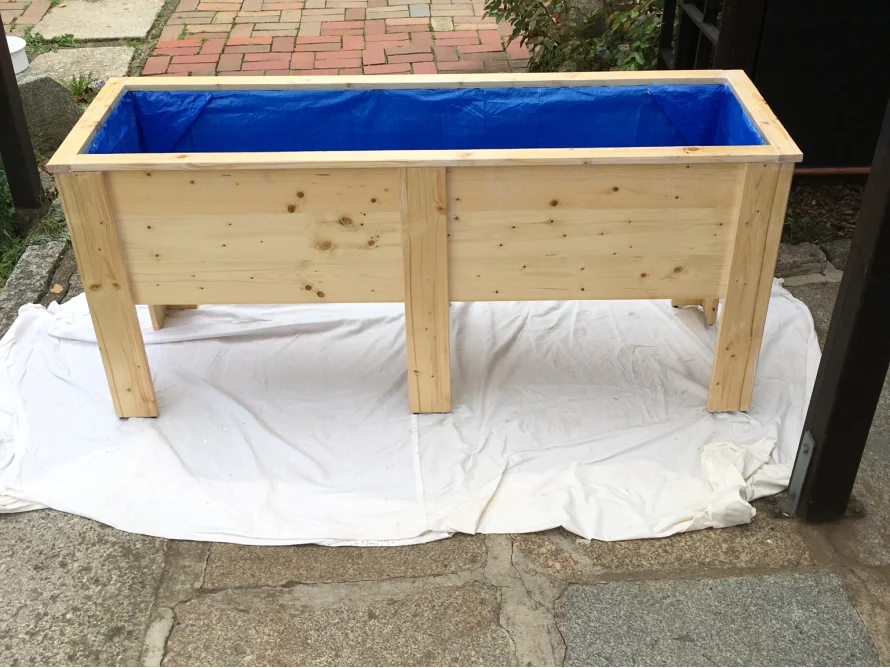 Hölzerner Blumenkasten mit blauer Folie ausgelegt