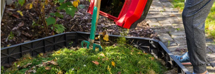 Person füllt Gartenabfälle in Komposter