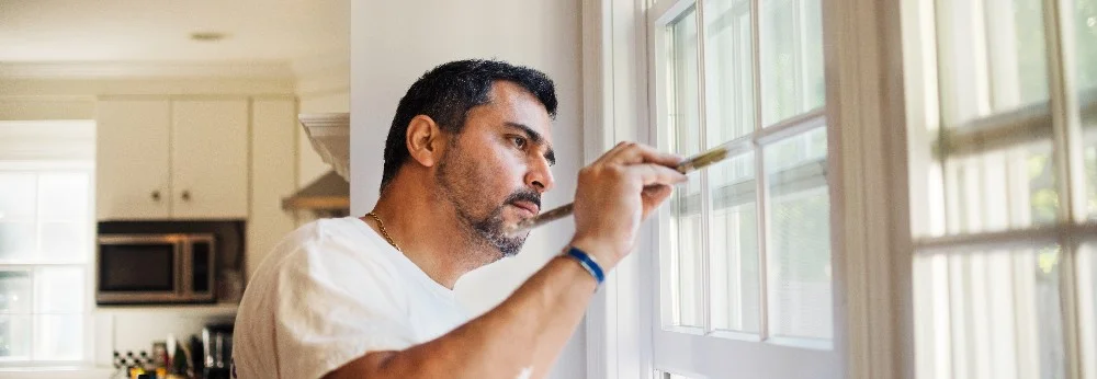 Person streicht Fensterrahmen