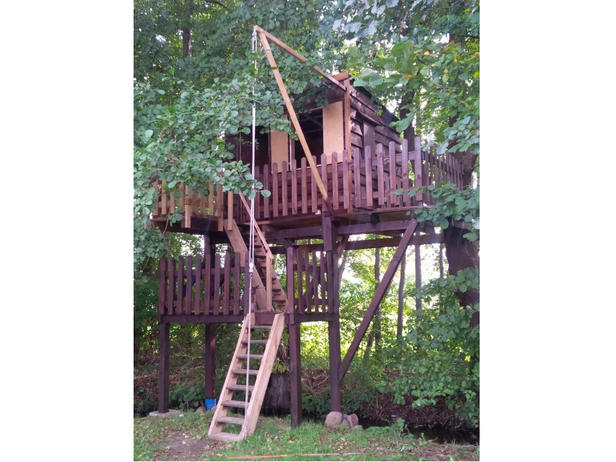 Ein Baumhaus aus Holz mit einer Leiter und einem Flaschenzug.