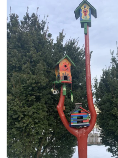 Drei bunte Vogelhäuser auf einem roten Stamm