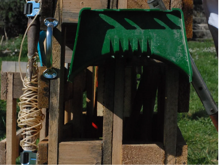 Gartenrechen und Gartenschere an Holzgestell
