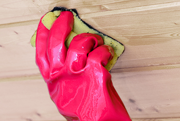 Hand mit Schwamm reinigt Holz