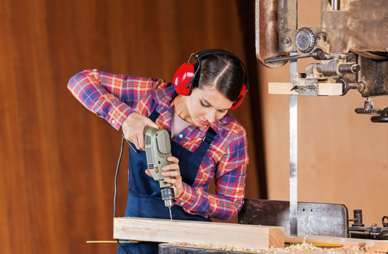 Person bohrt mit Bohrmaschine in Holz