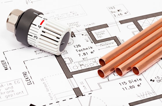 Kupferrohre und Heizungsthermostat auf einem Bauplan